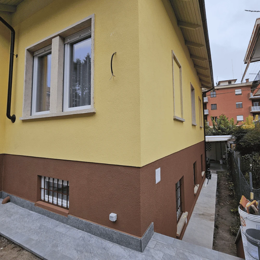 Vista laterale ristrutturazione facciata con serramenti PVC e pavimentazione esterna ad Alba